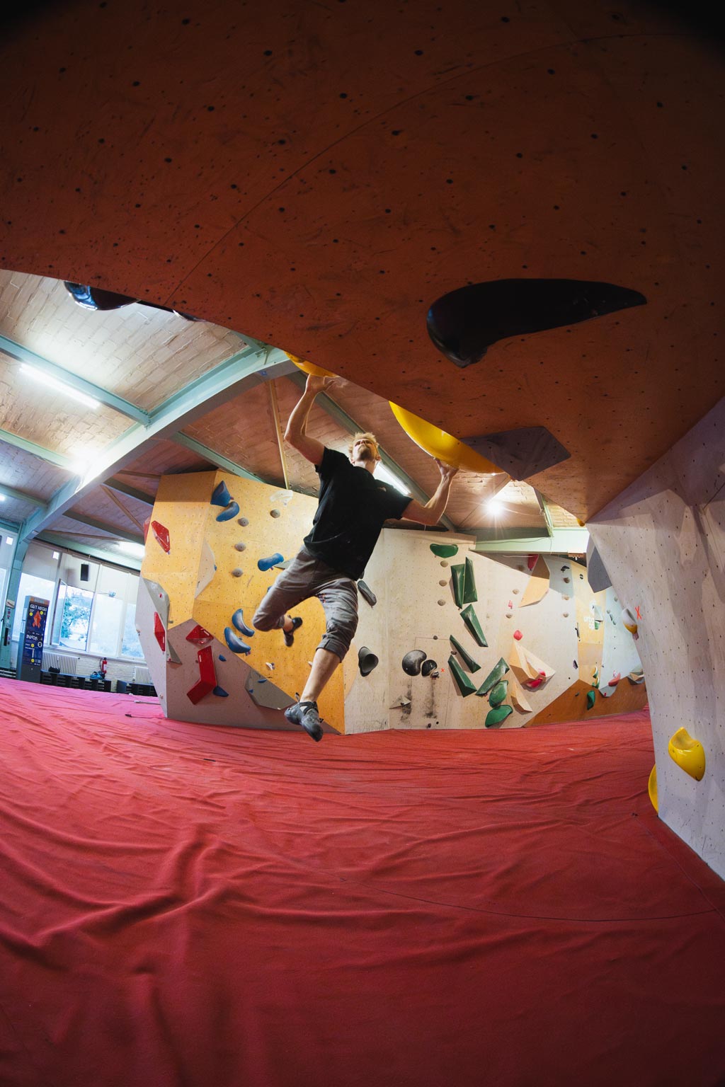 Mann klettert an einer Überhang-Boulderwand im urban apes bright site Berlin.