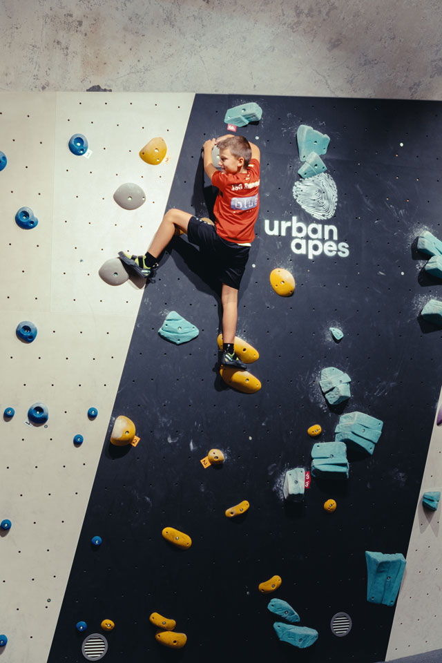 Junge an der Familienwand im urban apes Fhain Berlin. Ansicht von hinten.